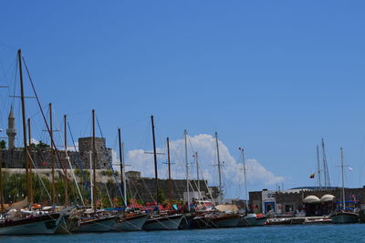Sailboats moored at harbor against clear blue sky