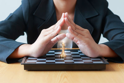 Midsection of businesswoman with chess board on table