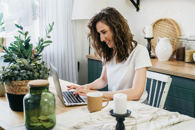 Beautiful woman in the kitchen working on a laptop.