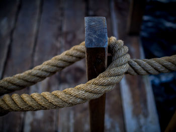 Close-up of rope tied on wooden post over pier