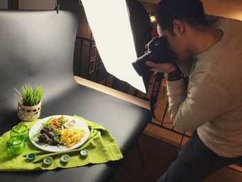 Side view of male photographer photographing food on backdrop