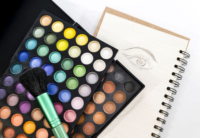 Close-up of eyeshadow and brush over book