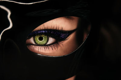 View of female batwoman green eye under black mask. beautiful make-up with glitter eyeshadow