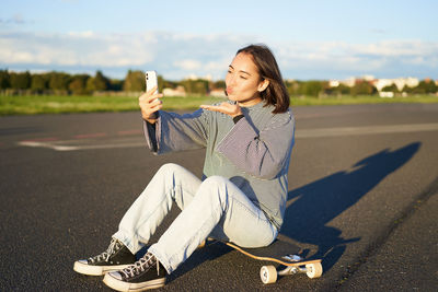 Portrait of young woman sitting on road