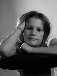 Portrait of teenager sitting on chair against gray background