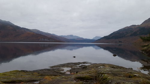 Scenic view of lake by mountains against sky