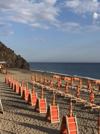 Row of chairs on beach against sky