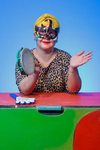 Portrait of young woman wearing sunglasses against blue background