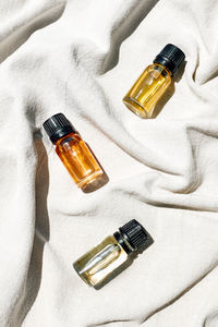 Natural essential oil, facial serum in cosmetic bottles with dropper on linen cloth.