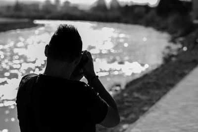 Rear view of man photographing river