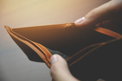 Close-up of hand holding book against gray background