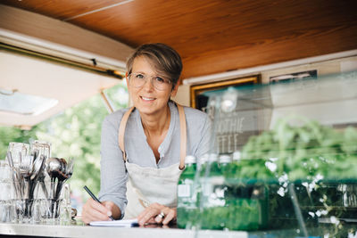 Portrait of mature owner taking order while standing in food truck