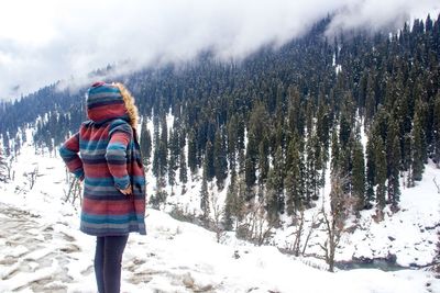 Rear view of woman standing on snow covered field