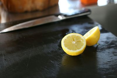 Close-up of halved lemons by knife on table