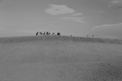 People walking on desert against sky