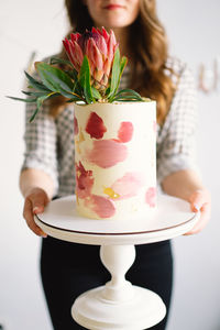 Young woman with birthday cake, close up. the cake is decorated with protea flowers.