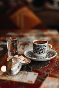 A cup of traditional black strong turkish coffee, sweets delight and a small glass of water. 