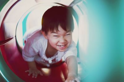 Portrait of happy boy playing in slide 