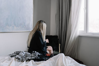 Woman sitting on bed at home