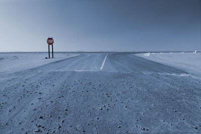 Road amidst snow covered land against clear sky