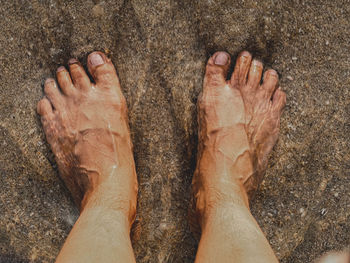 Low section of person standing on sand