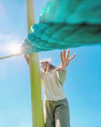 Low angle view of woman standing against sky on sunny day