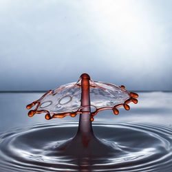 Close-up of water drop on sea against sky