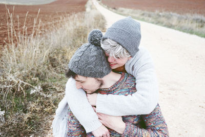 High angle view girlfriend embracing boyfriend on dirt road during winter