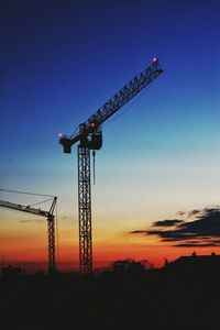 Low angle view of crane at construction site against sky during sunset