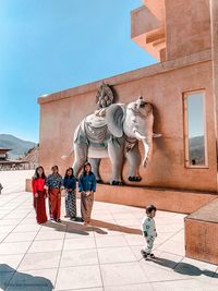 Statue of woman walking against building