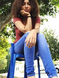 Portrait of young woman sitting on tree