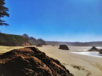 Scenic view of beach against clear blue sky