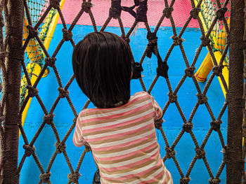 Rear view of girl against blue fence