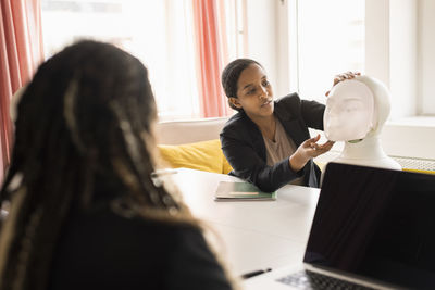 Businesswomen discussing robot voice assistant during meeting