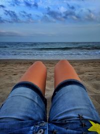Low section of man on beach against sky