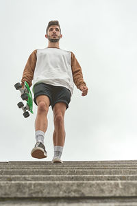 Young man getting down the stairs with a skateboard in his hand person