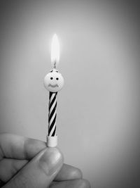 Close-up of hand holding candle against white background