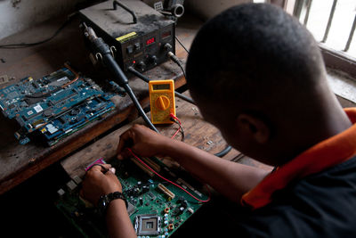 Young adult repairing a computer motherboard in a workshop