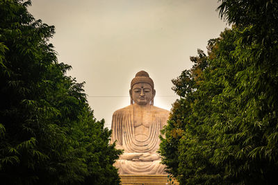 Statue of temple against trees against sky