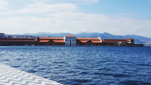Scenic view of lake by buildings against cloudy sky