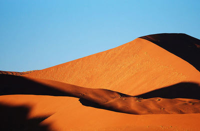 Sand dune in desert against clear sky