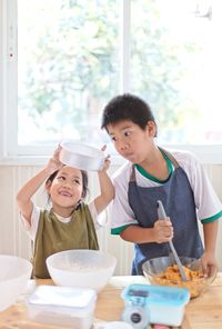 Playful siblings preparing food in kitchen