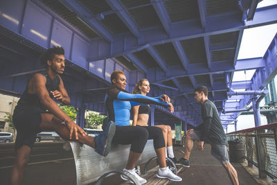 Friends exercising on bench in city