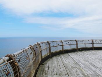 Love locks on railing of north pier over sea against sky