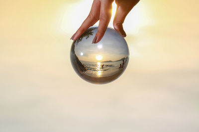 Digital composite image of hand holding crystal ball