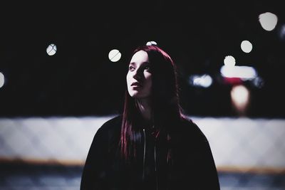Young woman looking away against sky at night