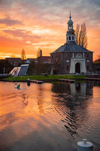 Reflection of building on water against orange sky