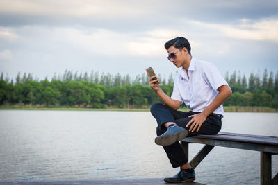 Full length of man using smart phone against sky