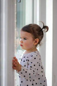 Little girl with ponytails looks out the window. new home rental.