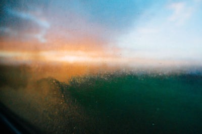 Raindrops on glass window during sunset